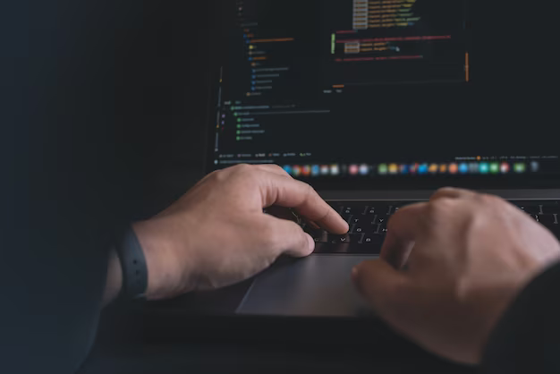 Man's hands on the keyboard of a laptop on the screen of which the program code