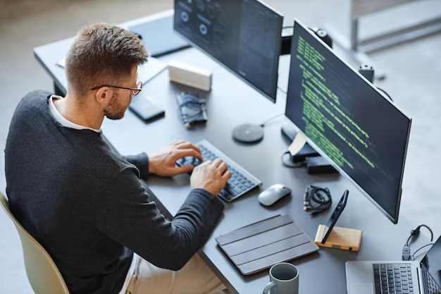 A man works on a computer and writes program code