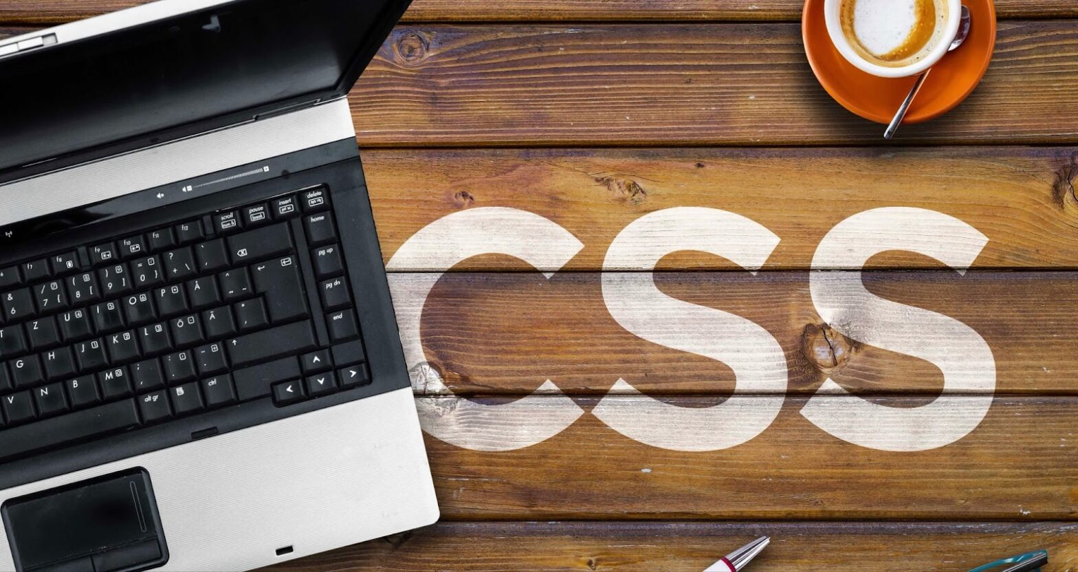 CSS on a wooden table next to a computer